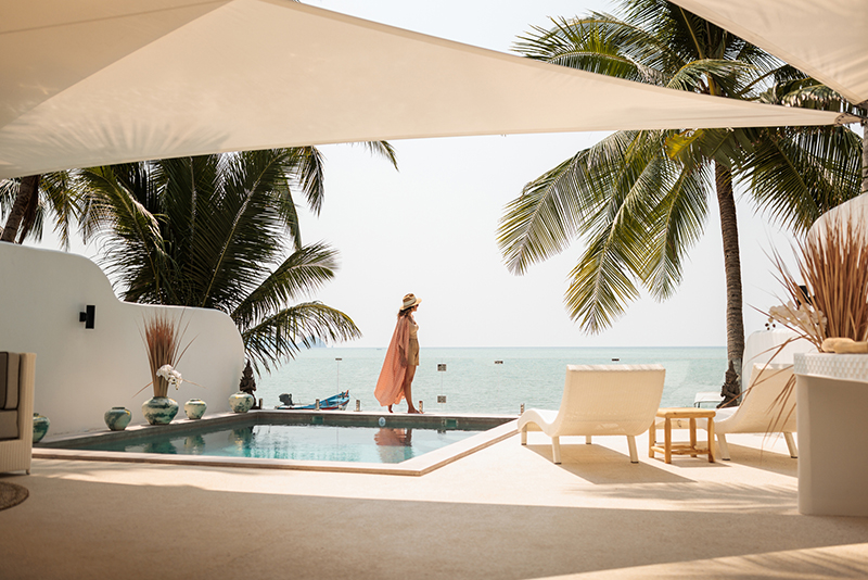 Woman enjoy a leisurely moment by the swimming pool at a luxurious villa on the beach.